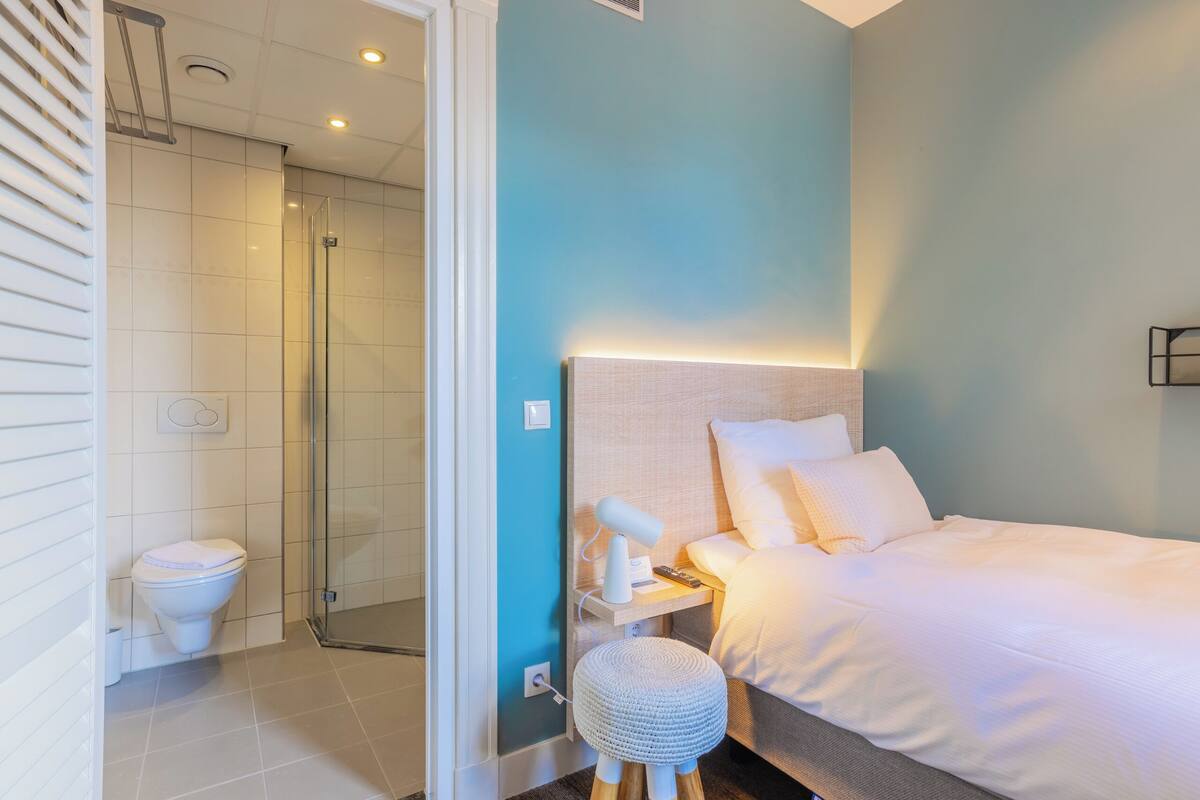 Une salle de bain moderne équipée d’une douche, de toilettes et d’une table de chevet avec une lampe.