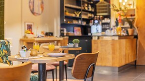 Een gezellig restaurant met houten meubels, een bar en diverse decoratieve objecten op planken.