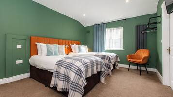 A bedroom with two beds, a chair, and a window with curtains.