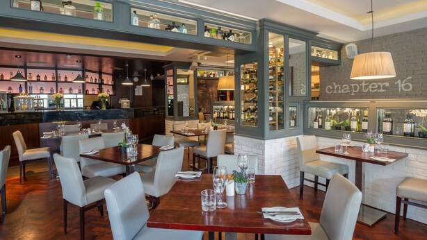 A restaurant with multiple dining tables, chairs, and a bar area with shelves of bottles. - Silken Thomas (Kildare)