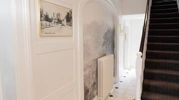 A hallway with a framed historical photograph, a radiator, and a staircase.