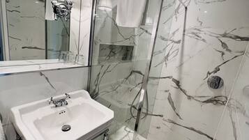 A bathroom with a marble sink, a glass shower enclosure, and a large mirror.