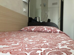 A hotel room with a bed, a desk, a chair, and a door. - Brenta Milano (Milan)