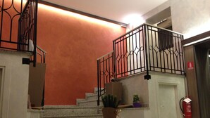 A staircase with a metal railing, a potted plant, and a fire extinguisher. - Brenta Milano (Milan)