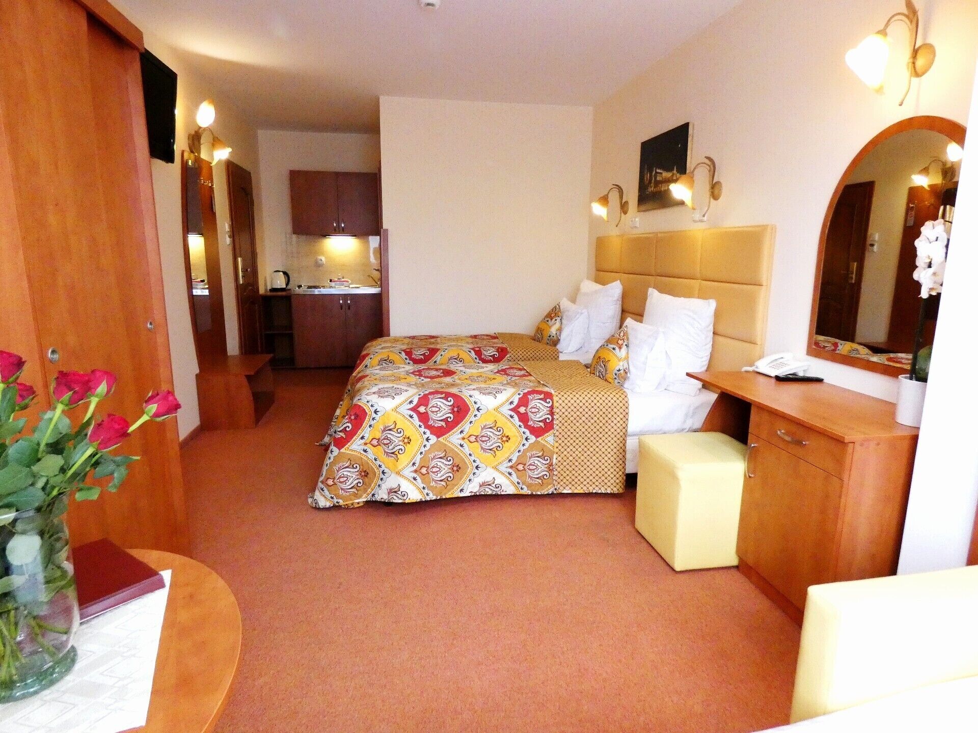 Ein Hotelzimmer mit Bett, Nachttisch, Spiegel und kleinem Schreibtisch mit Stuhl.