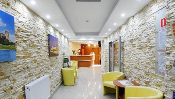 A hotel lobby with stone walls, a reception desk, and yellow seating. - Aparthotel Adler (Kraków)