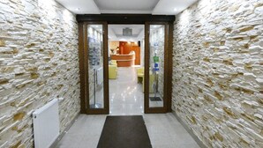 A hotel lobby with stone walls, a reception desk, and a waiting area with chairs. - Aparthotel Adler (Kraków)