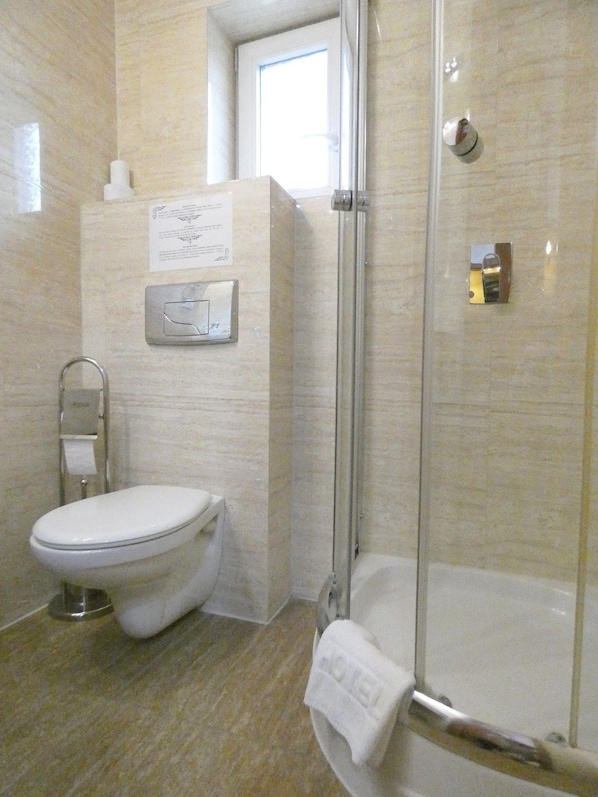 A bathroom with a toilet, a shower, and a glass-enclosed shower stall. - Aparthotel Adler (Kraków)