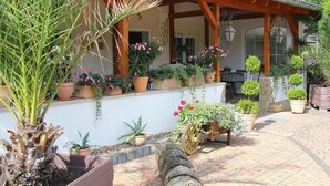 Un patio techado con plantas en macetas y un barril de madera.
