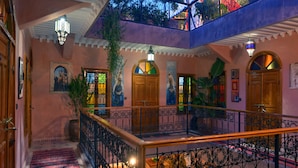 Un intérieur à plusieurs niveaux, avec un escalier, des portes en bois et des rampes de fer décoratives.