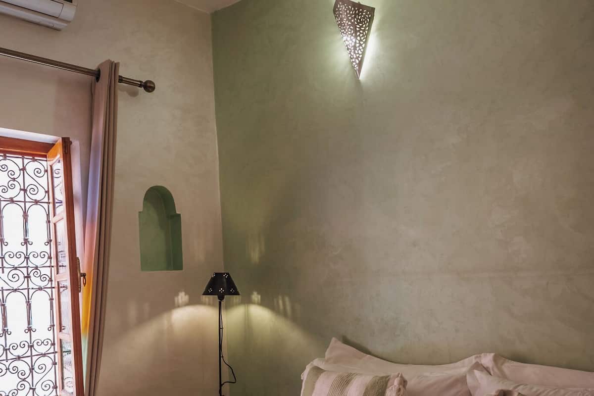 Une chambre à coucher comprenant un lit, des oreillers, une lampe, une commode et un élément décoratif mural.