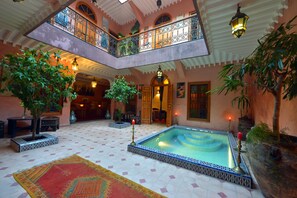 A spacious atrium with a central pool, multiple balconies, and lush indoor plants. - Riad Zayane Atlas (Marrakech)