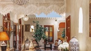 Un intérieur traditionnel agrémenté d’un tapis à motifs, d’une lanterne suspendue et d’une table en bois sur laquelle est posé un vase.