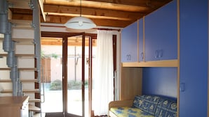 Una habitación con escalera de madera, cama con colcha estampada y armarios azules.