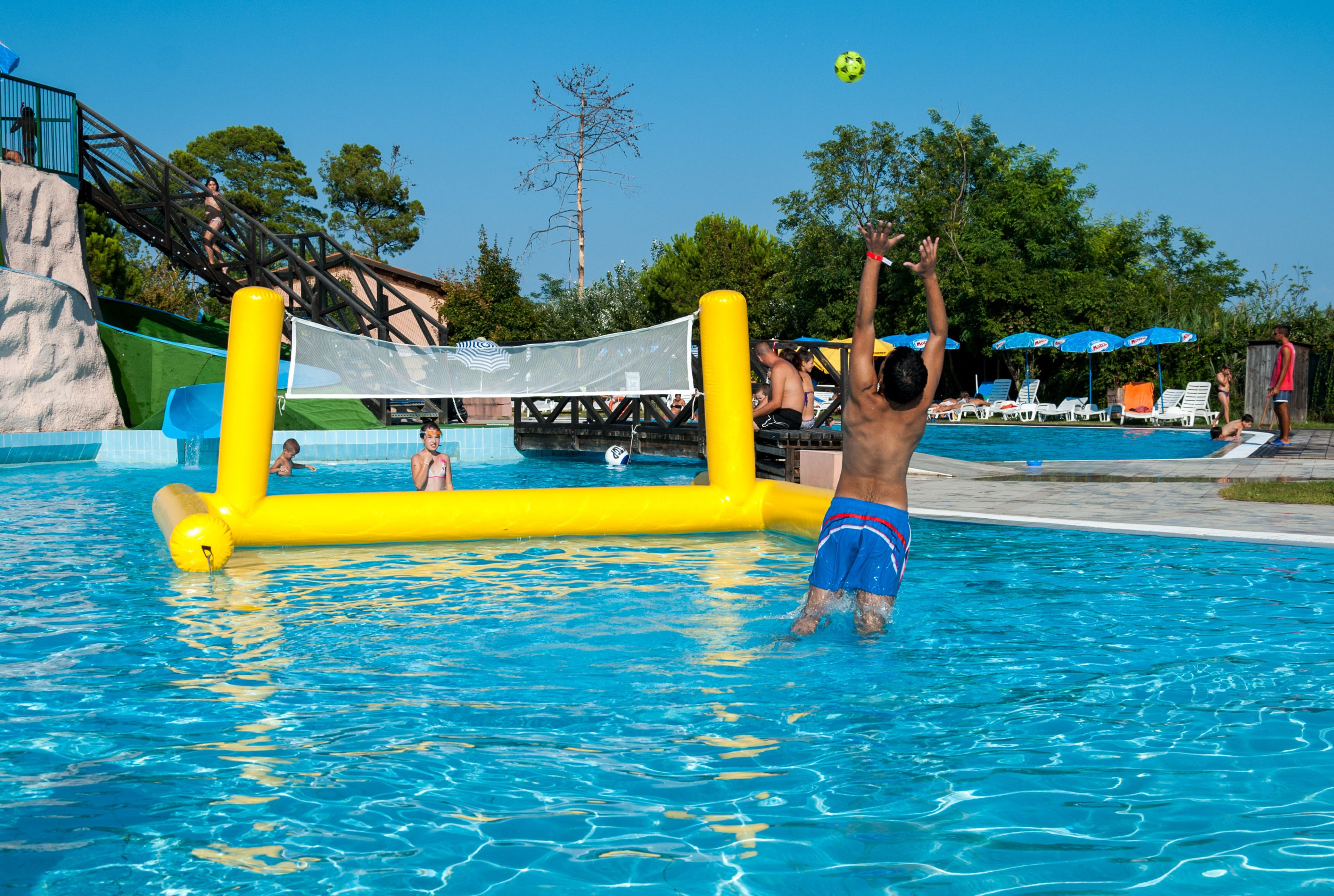 A swimming pool with inflatable structures and a water slide.