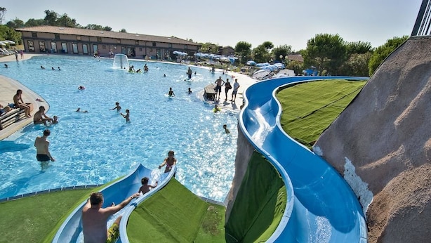 Una piscina con múltiples toboganes y una zona verde.