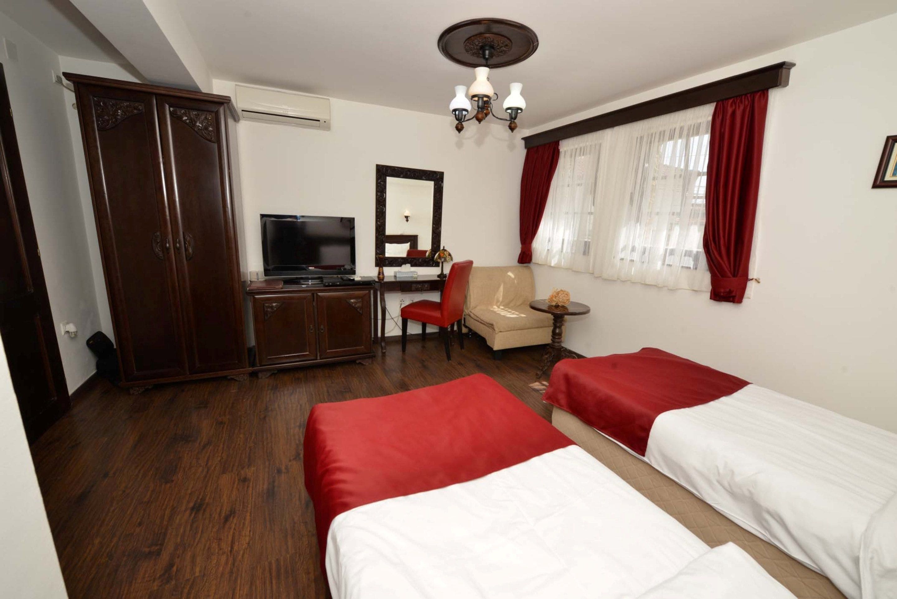 Une chambre d’hôtel avec deux lits, une télévision, un bureau, une chaise et une armoire.