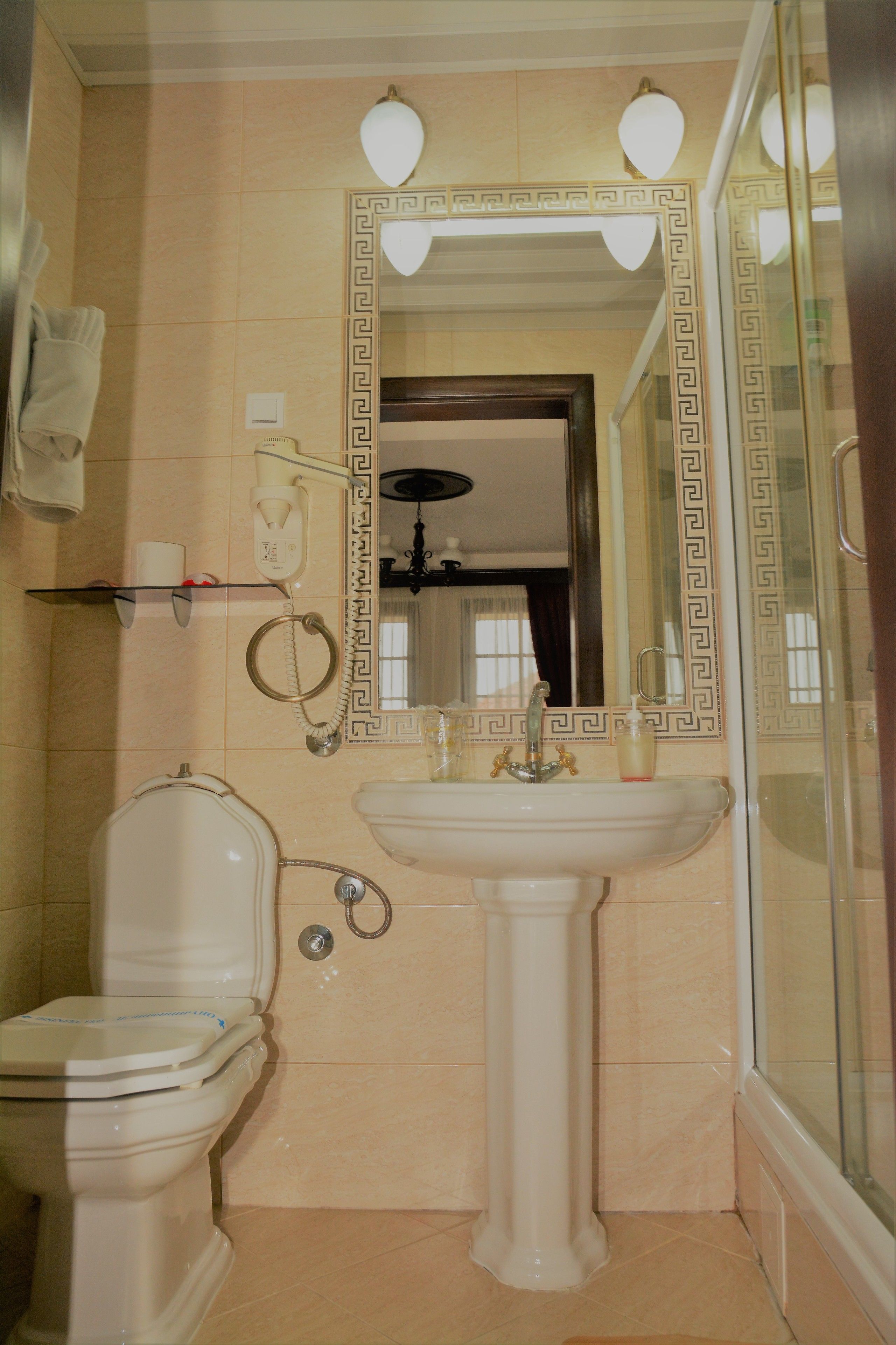 A bathroom with a toilet, sink, and mirror.