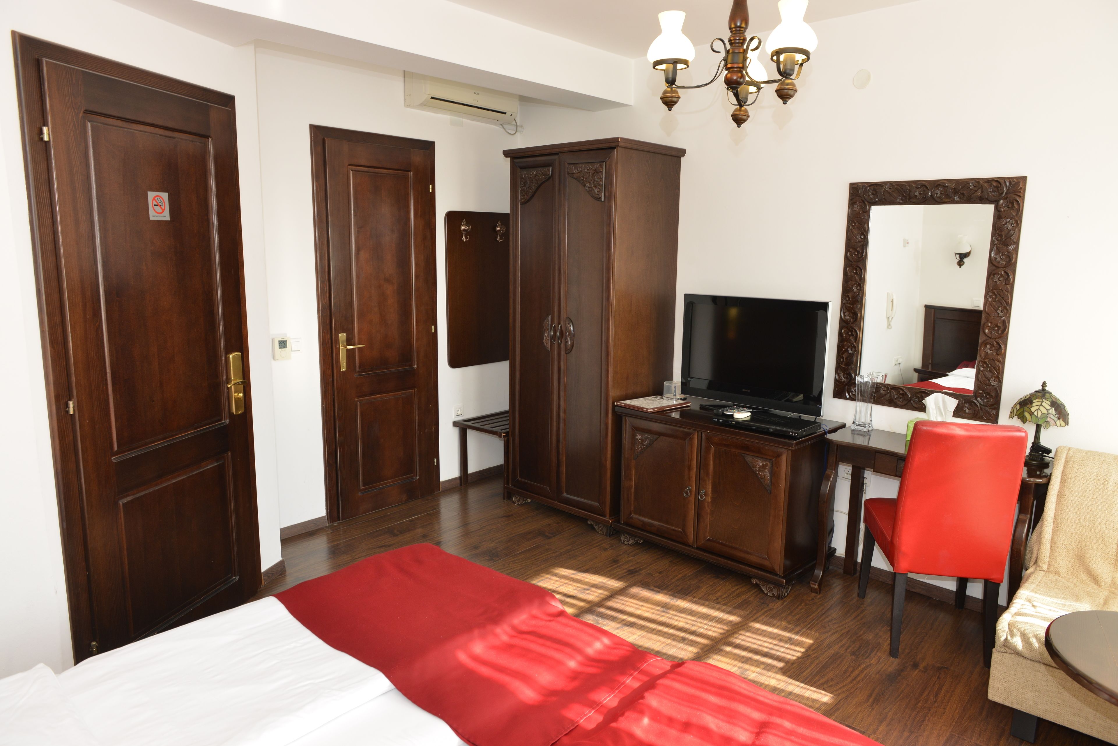 Habitació d'hotel amb un llit, una taula de treball amb televisió, un armari i un mirall.