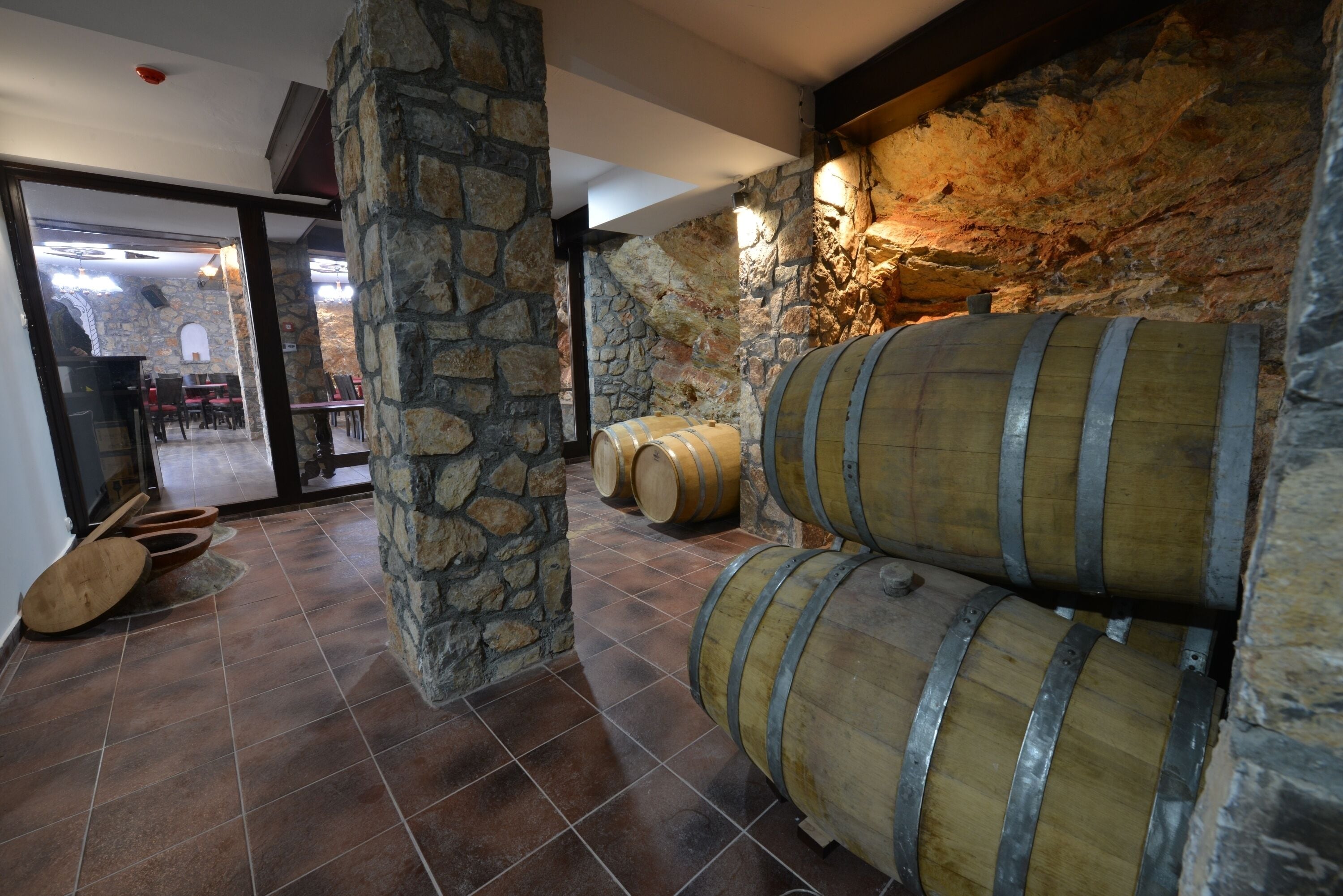 Una bodega con paredes de piedra, barriles de madera y piso de baldosas.