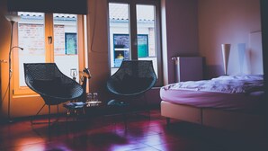 A bedroom with a bed, two chairs, a small table, and a radiator. - Themen Hotel zur Kranengasse (Kranenburg)