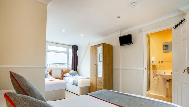 Une chambre d’hôtel avec deux lits, une télévision, une salle de bain et une fenêtre avec des rideaux.