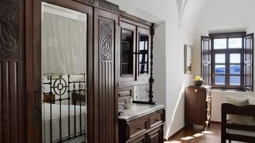 Una habitación con una cama, un tocador de madera, un espejo y una ventana con vistas.