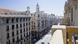 A street view of a city with historic buildings, a prominent tower, and a clear sky. - Hostal Galaico (Madrid)