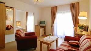 Een woonkamer met twee rode banken, een houten salontafel, een televisie en een kroonluchter.