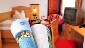 Een kamer met een bed, een televisie, leesvoer en een kleine tafel met een lamp.