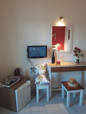 Ett litet rum med ett skrivbord, en stol, ett litet bord och en tv.