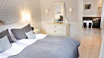 A neatly arranged bedroom with a large bed, bedside tables, a dresser, and a mirror.