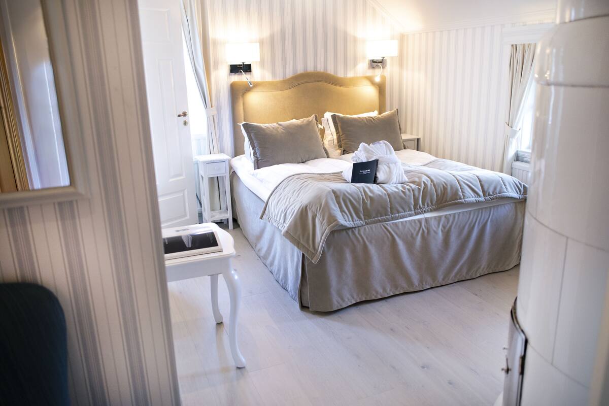 Ein Hotelzimmer mit einem großen Bett, zwei Nachttischen und einem Beistelltisch.