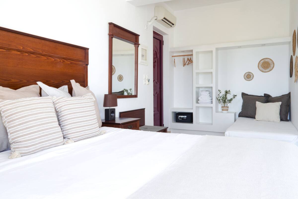 Une chambre d’hôtel avec un grand lit, une table de chevet, un miroir, une armoire et une petite plante sur la table de chevet.