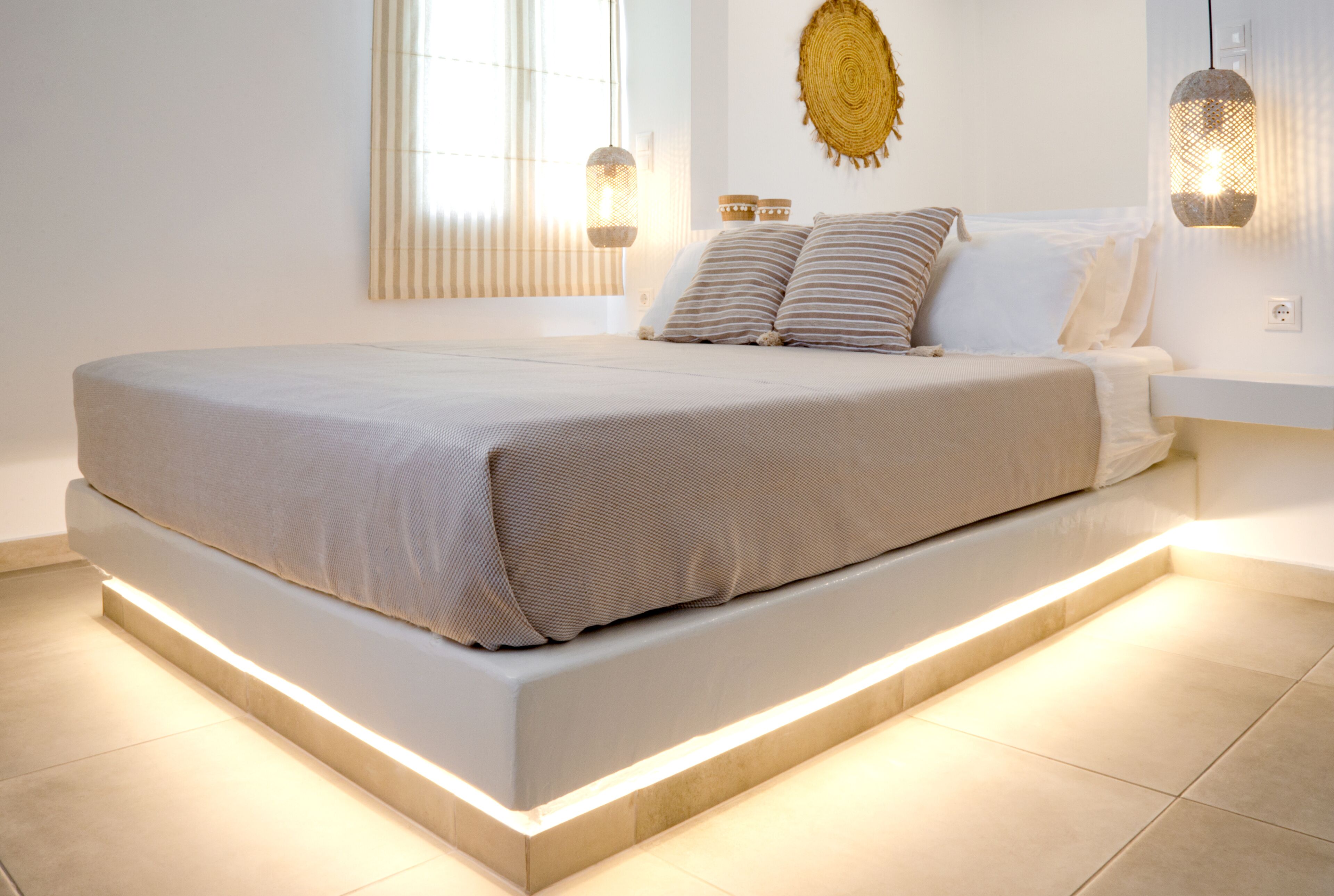 Un dormitorio moderno con una cama grande, lámparas de noche y un elemento decorativo en la pared.
