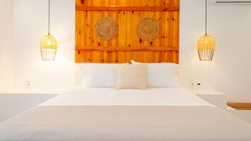 A bed with white linens, two woven lamps, and a wooden headboard with circular wall decorations.