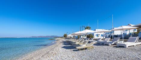 Na praia, espreguiçadeiras, guarda-sóis, bar na praia