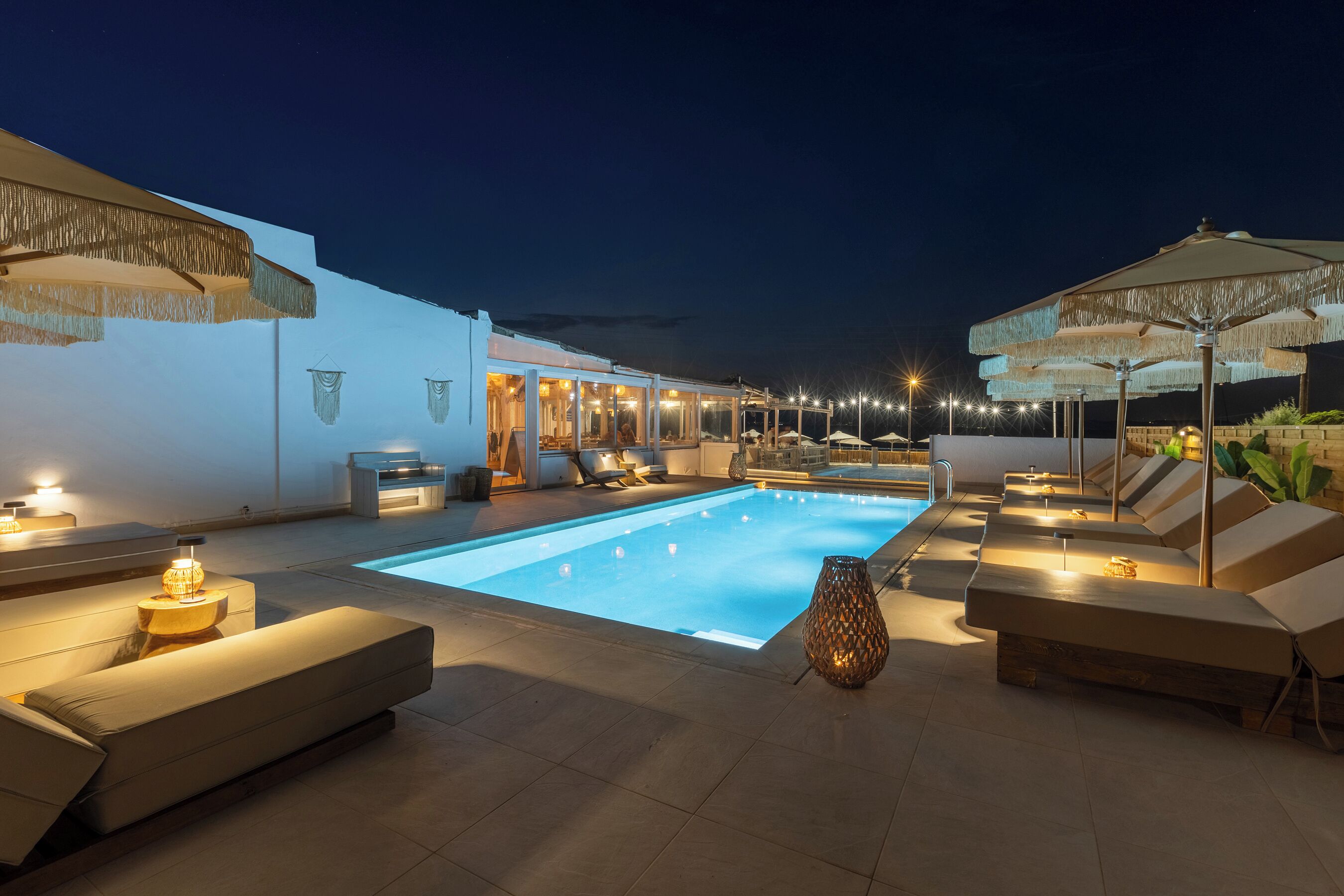 Un espace aménagé au bord de la piscine, avec des chaises longues, une piscine et un éclairage d’ambiance.