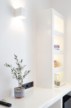 A modern kitchen with a white countertop, a potted plant, a remote control, and a built-in shelf unit.