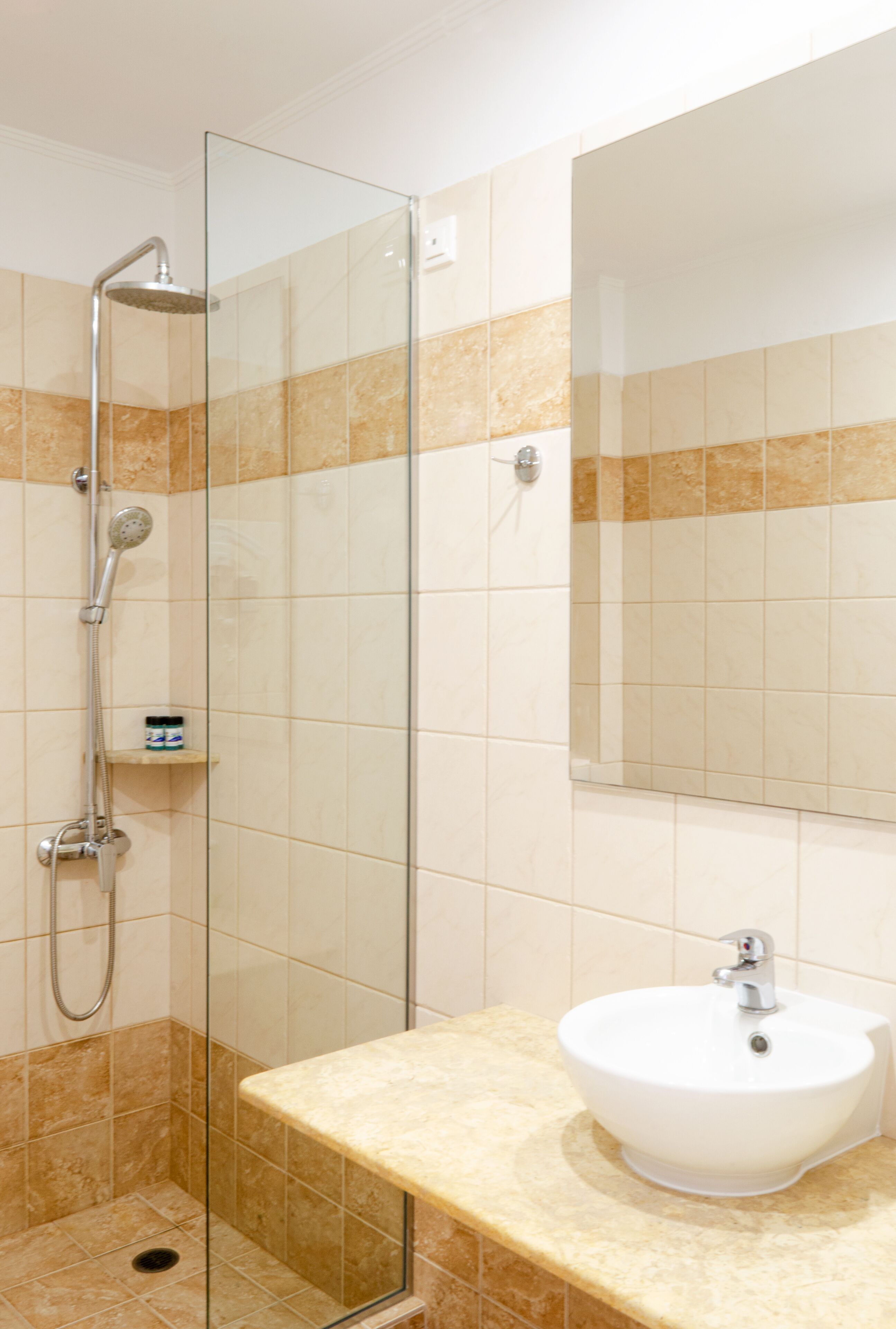 A bathroom with a glass-enclosed shower, a sink, and a mirror.