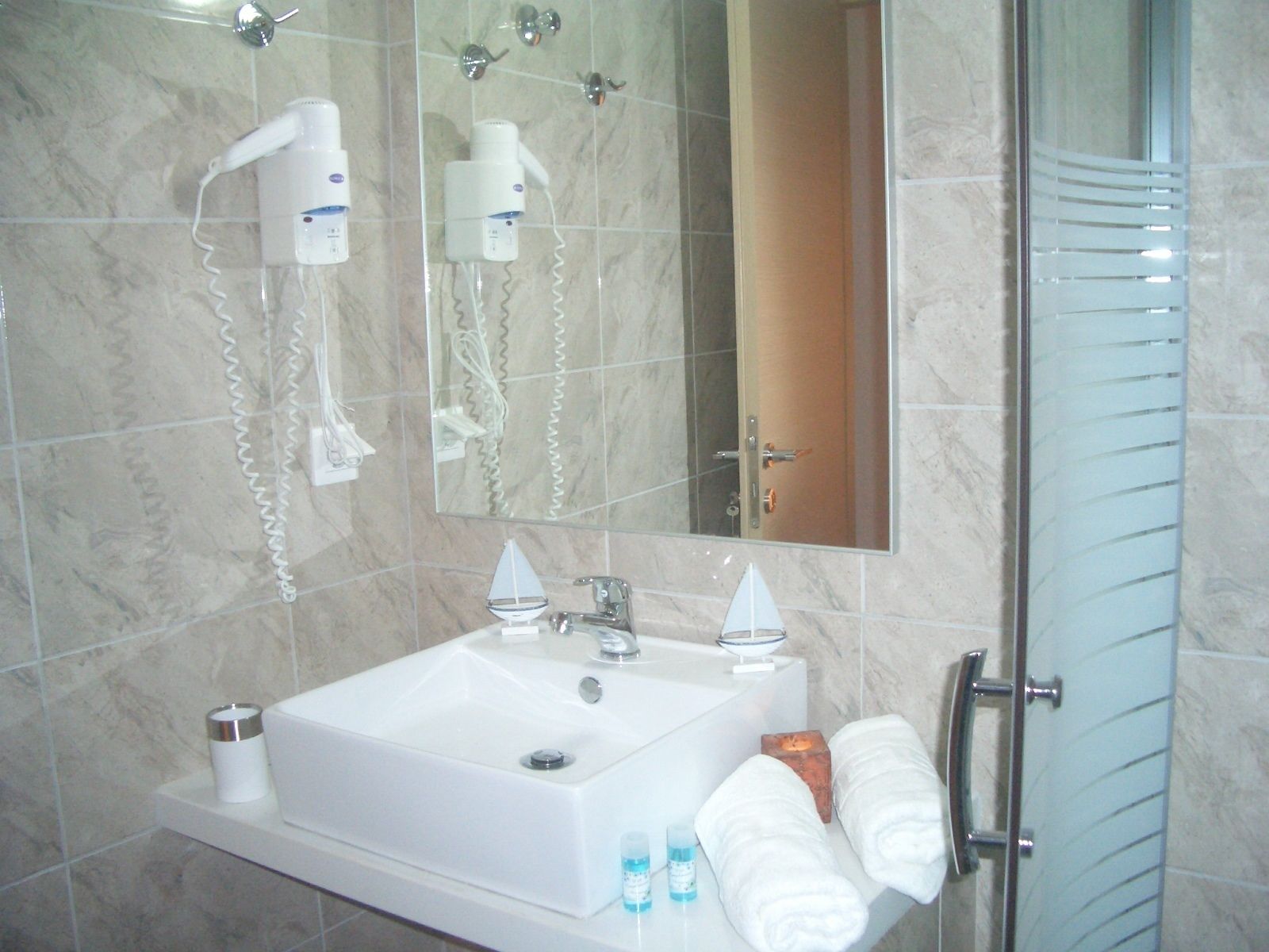 Baño con lavamanos, espejo, toallero y secador de pelo.