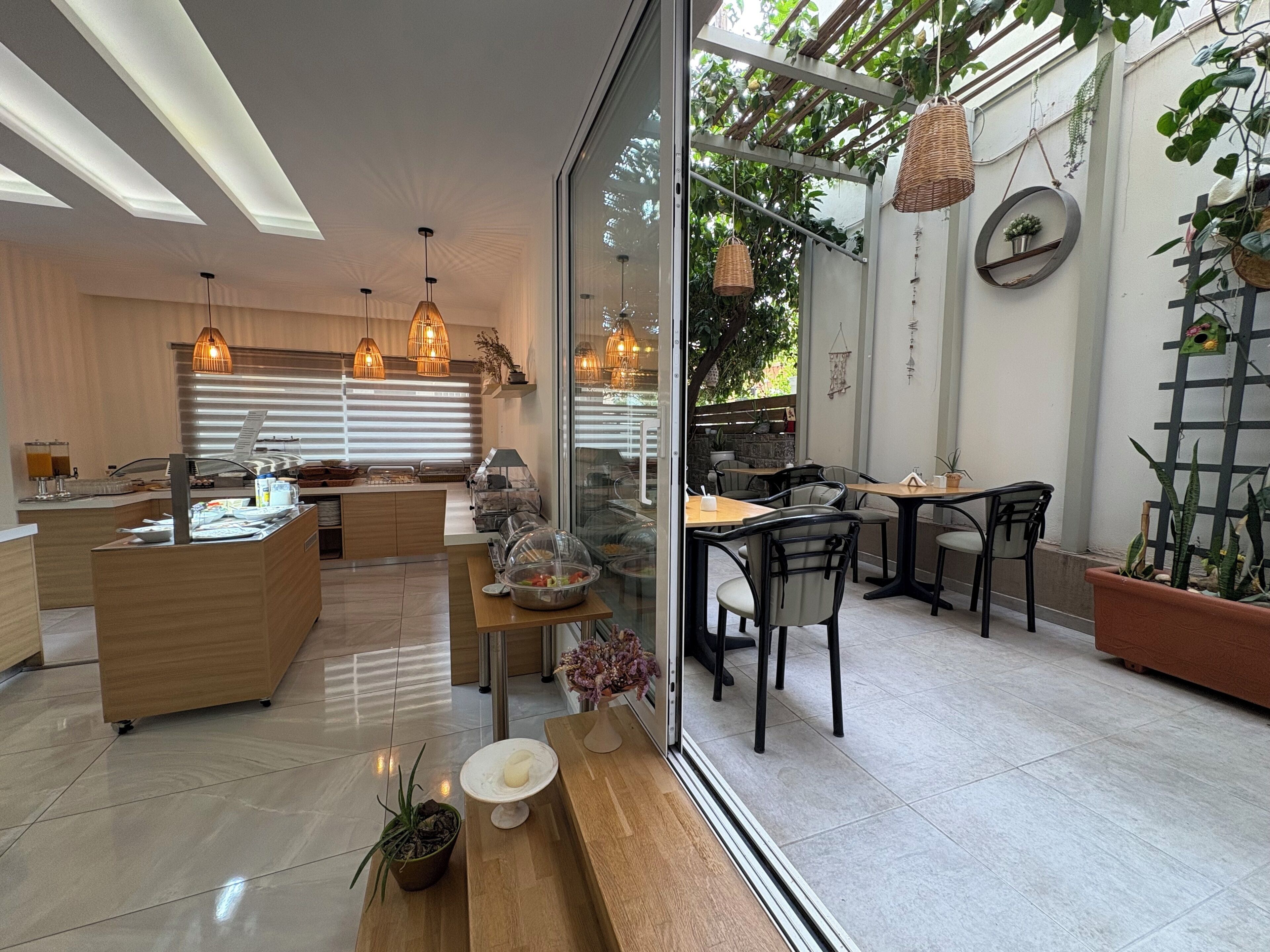 A modern kitchen with a breakfast bar, dining area with chairs, and a view of the outdoors.
