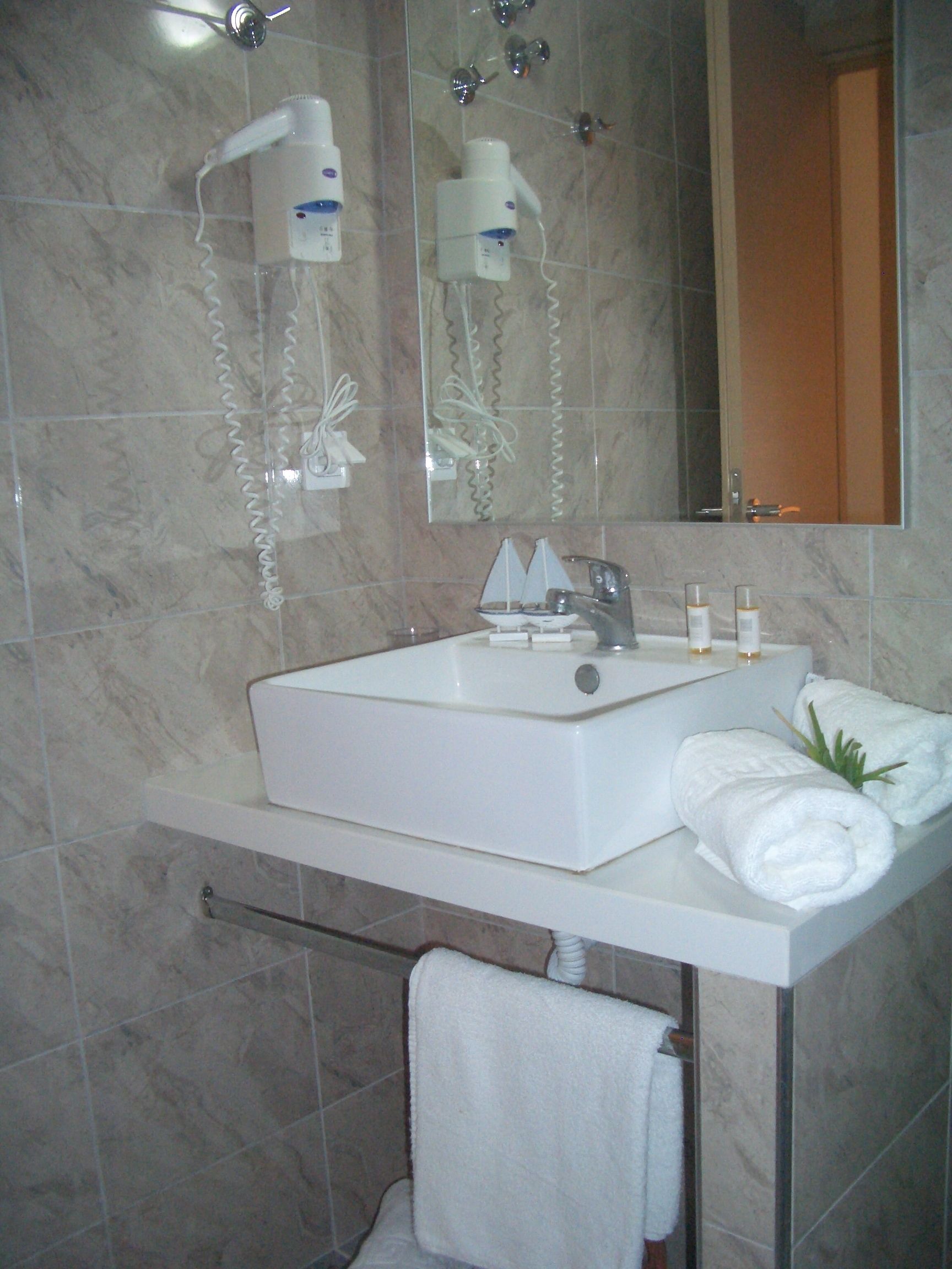 A bathroom with a white sink, a mirror, and a towel rack.