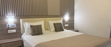 A hotel room with a bed, bedside tables, and a wall-mounted light fixture.
