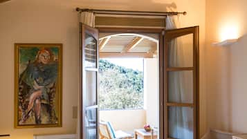Un dormitorio con cama, ventilador de techo, un cuadro y vistas al exterior.