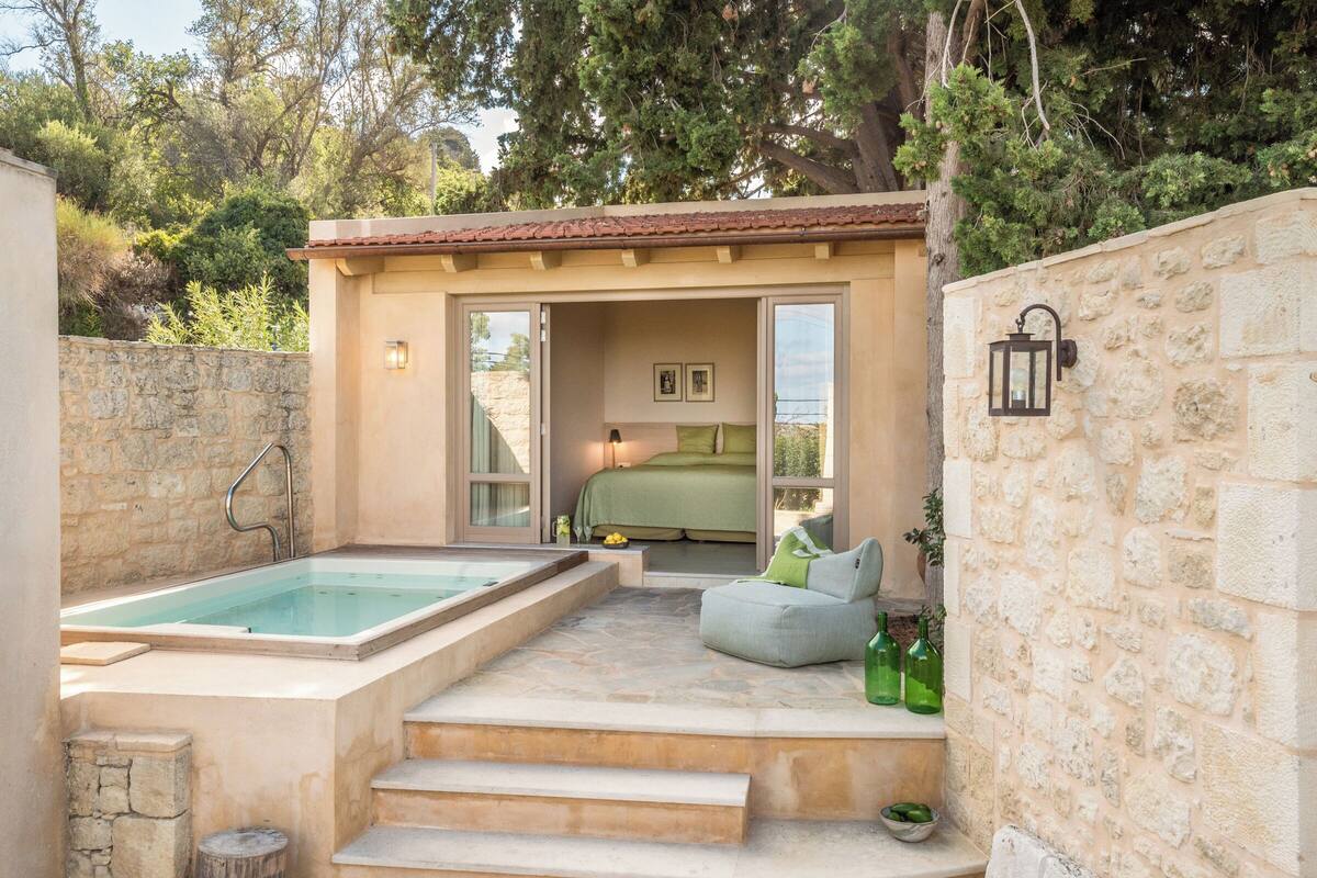 A spa area with a hot tub, a seating area with cushions, and a bed visible through an open door.
