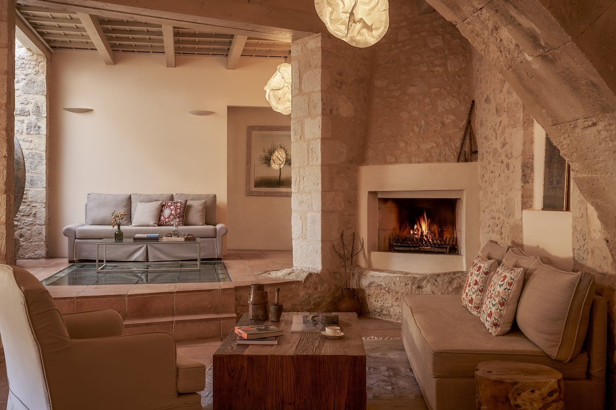 A cozy living room with a stone fireplace, a sofa, and a coffee table.