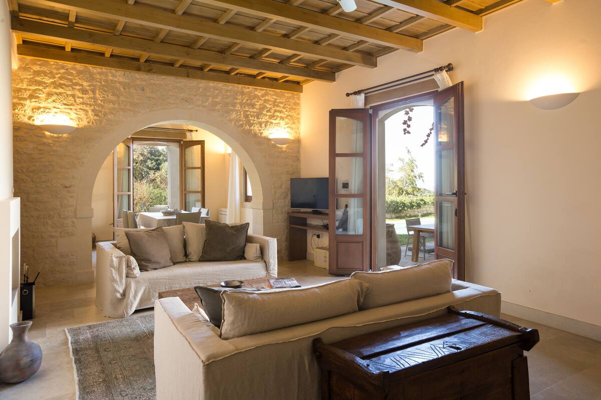 A cozy living room with a stone archway, a sofa, a wooden bench, and a television.