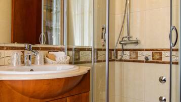 A bathroom with a glass-enclosed shower, a wooden vanity with a sink, and a mirror.