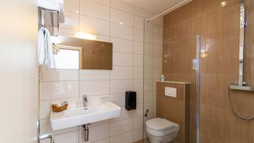 Un bagno moderno con lavandino bianco, specchio e cabina doccia in vetro.